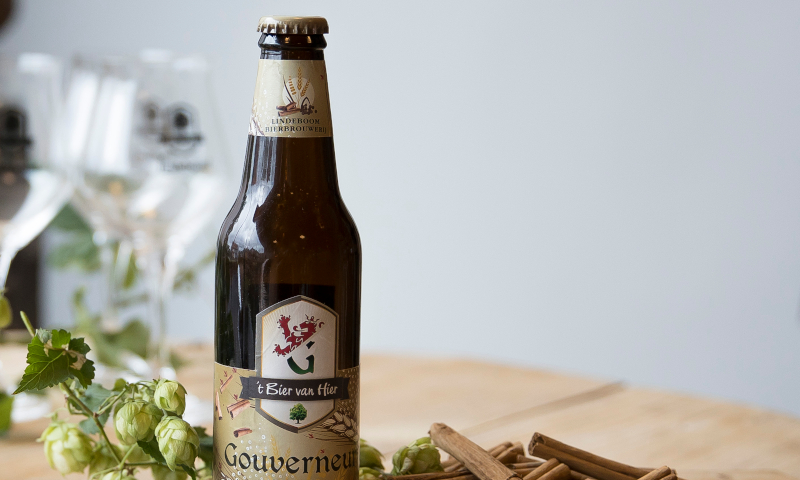 Gouverneur Tripel flesje tussen kaneelstokjes en hopbloemen